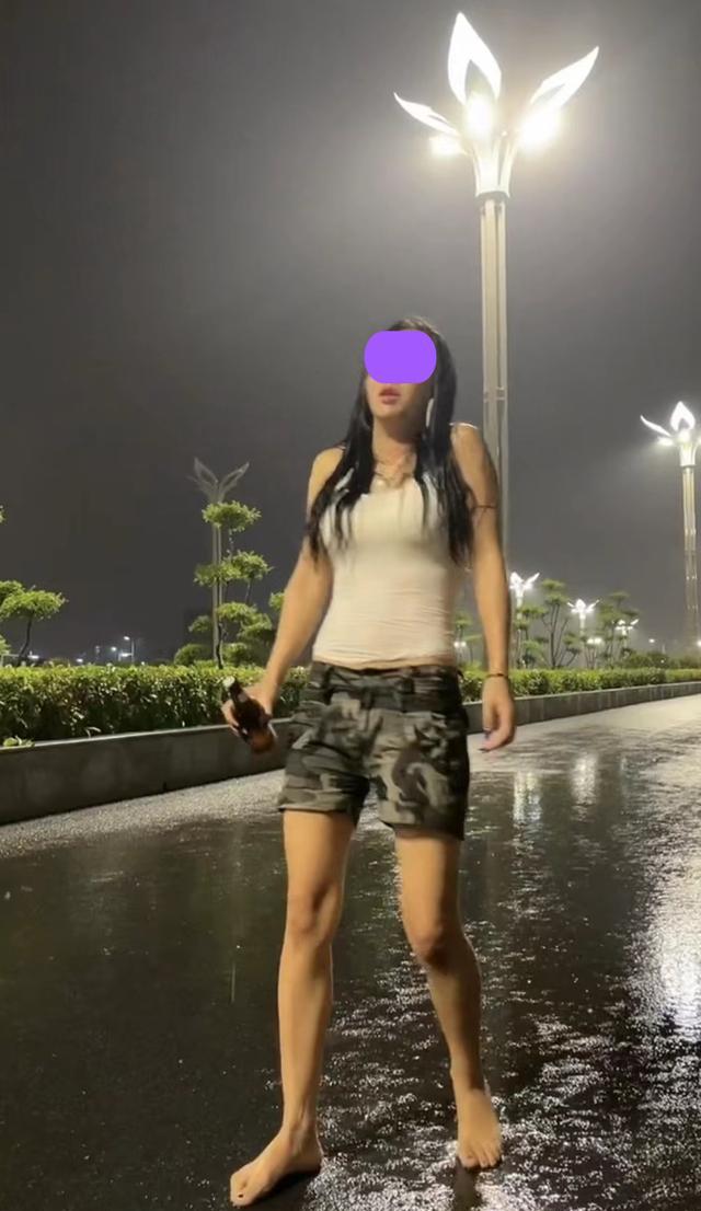 一女子为了缓解压力,光着脚丫走在马路上,手上还抓着一瓶啤酒