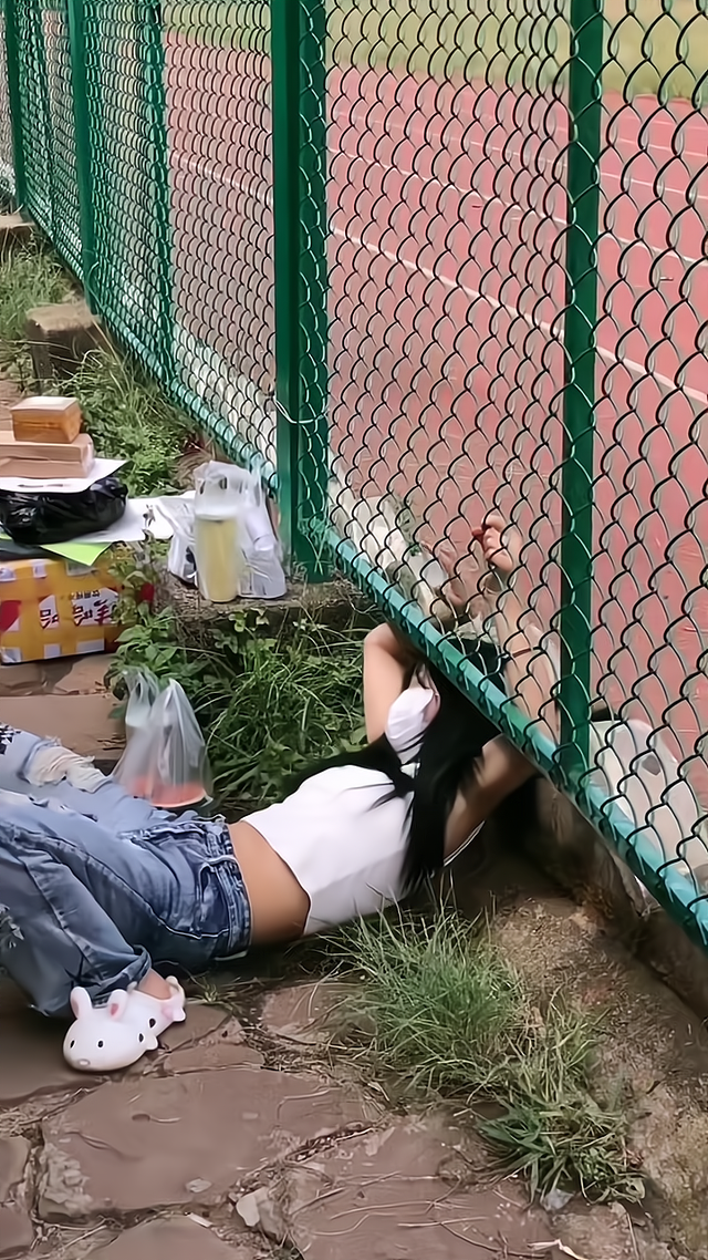 学校不允许外出,一女子为了拿快递,直接从围网下面钻出去