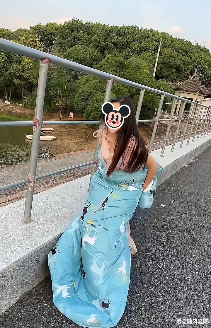 女子担心大风掀起她的裙子,蹲在原地不敢动,男子送被子给她裹身
