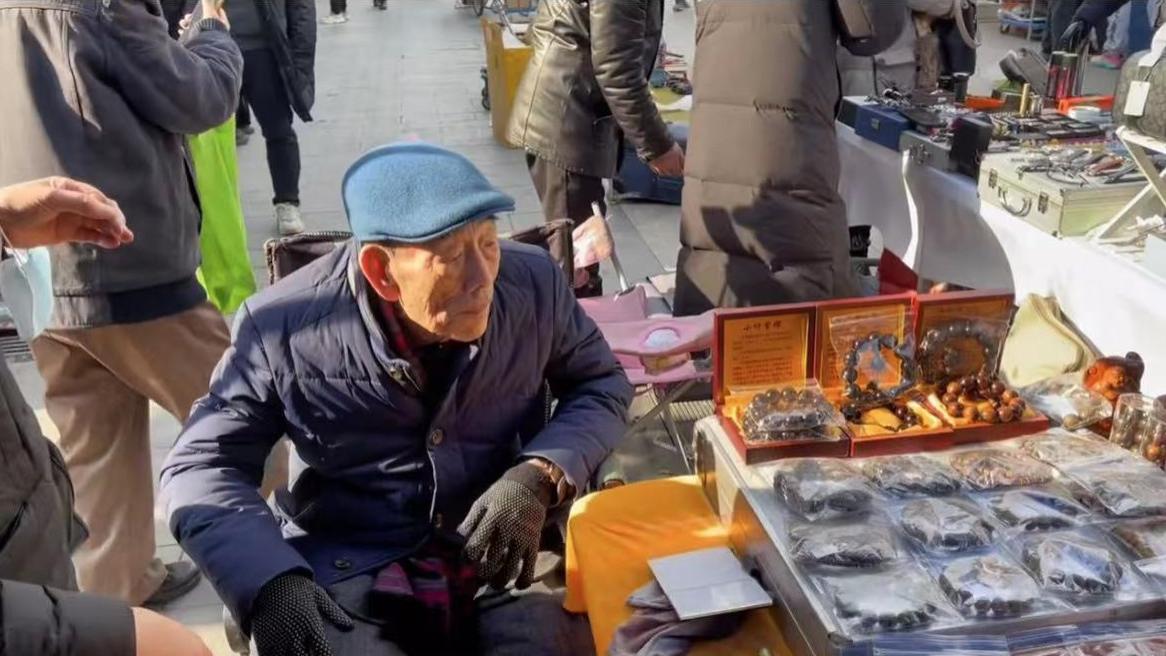 90岁杨少华在天津街头摆摊，坐轮椅穿厚袄清点货物，获众人围观