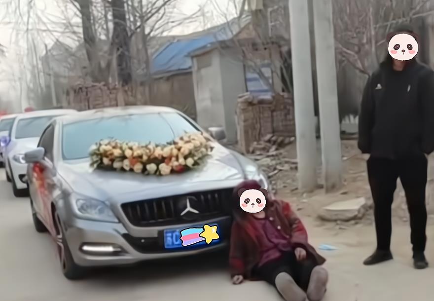 大妈拦住婚车要红包,不给钱就躺车轮底下,被人抬到路边继续躺