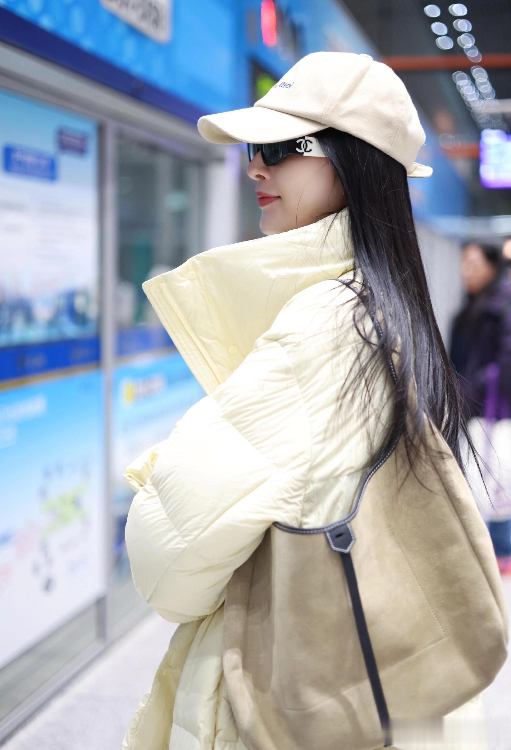张俪最新机场美照，穿奶黄色羽绒服戴着墨镜，长发飘飘又美又温柔
