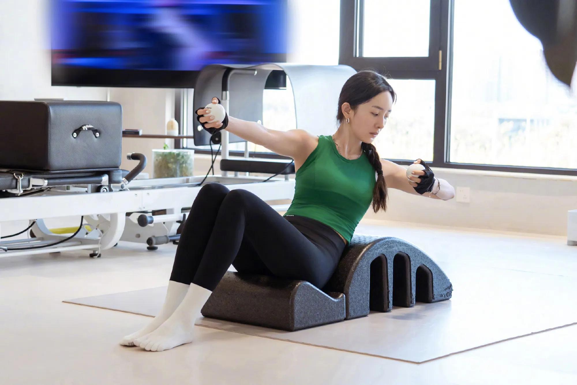 杨幂摆出S曲线坐泳池边，她扎了一头的小辫儿，她踮起脚尖比心美