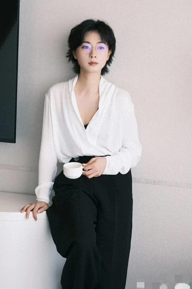 万茜身着白衬衫与阔腿黑裤,手持白色杯盏,松弛姿态尽显优雅气质