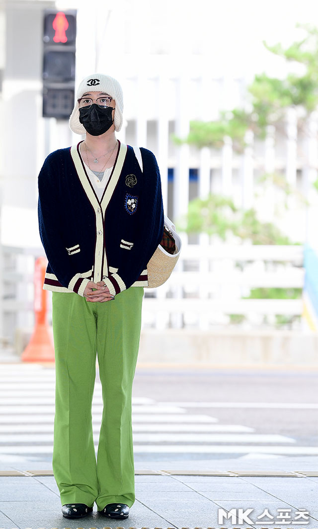 权志龙穿蓝色针织开衫，戴白色无檐帽，荧光绿阔腿裤吸睛
