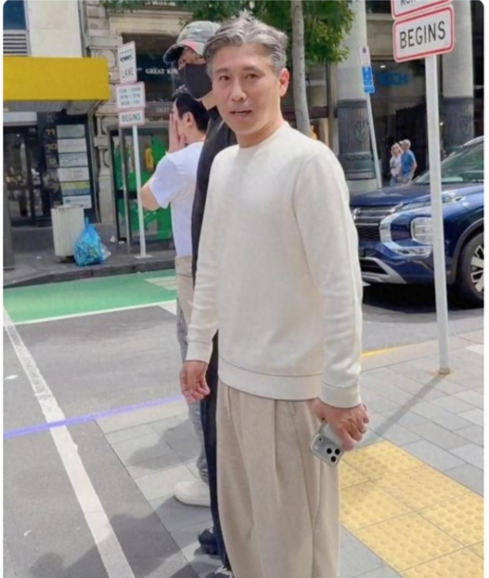 51岁李乃文现身新西兰，他穿白色卫衣，头发花白，状态不错。