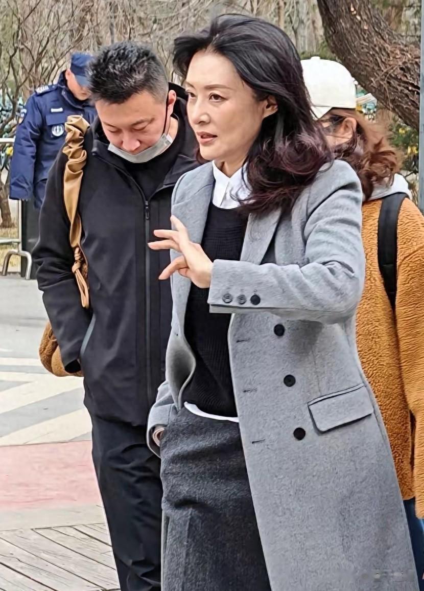 58岁周涛在北京朗园游玩，穿长筒靴和灰大衣，一头长卷发气质非凡